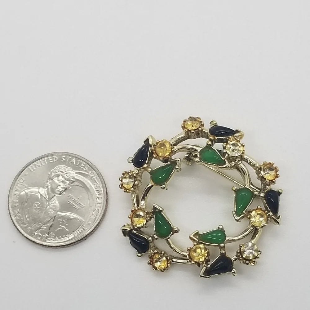 gold tone wreath brooch with clear green and black accents